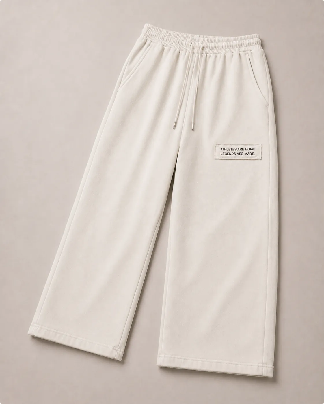 MADE Sweatpant in bone, flat lay, wide straight leg with the white legacy patch reading “Athletes are born. Legends are made.” on the wearer's left upper thigh