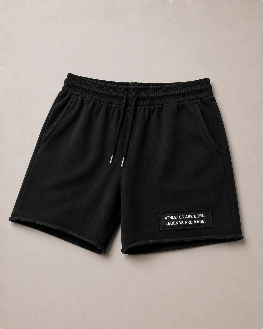 MADE Athlete Short in black, flat lay, showing the raw hem and the legacy patch reading “Athletes are born. Legends are made.” on the wearer's left leg