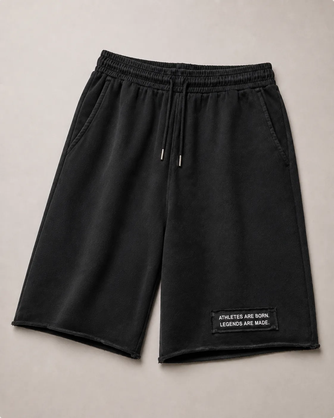 MADE Long Short in black, flat lay, knee length with a raw hem and the legacy patch reading “Athletes are born. Legends are made.” on the wearer's left leg