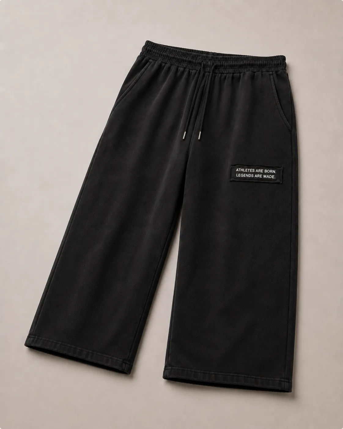MADE Sweatpant in black, flat lay, wide straight leg with the black legacy patch reading “Athletes are born. Legends are made.” on the wearer's left upper thigh